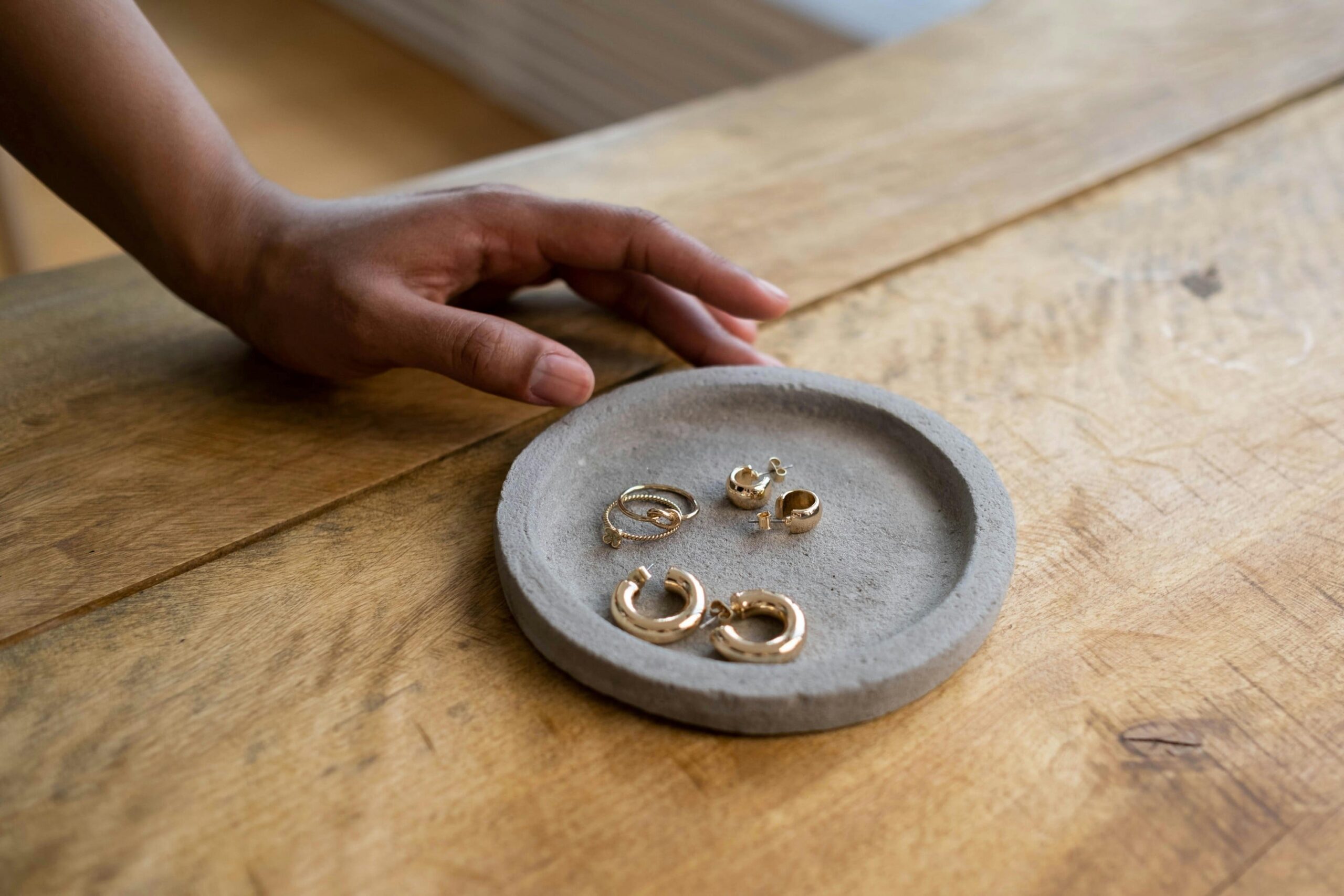 a clay dish with three pairs of gold huggie earrings on top