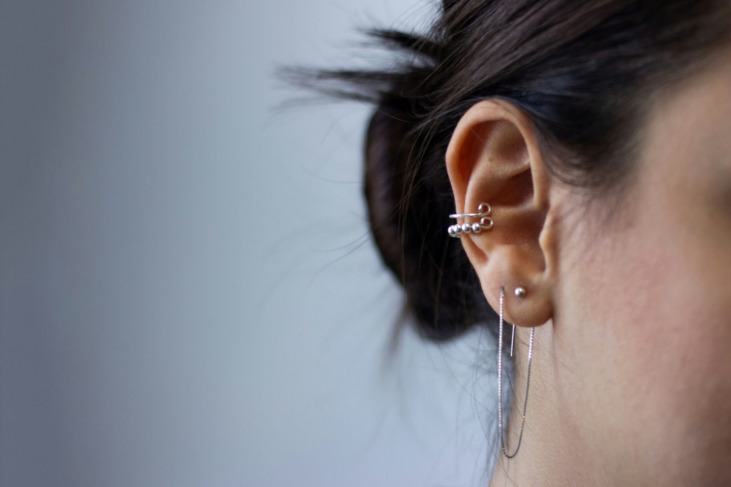 a close up of a womans ear showcasing three different piercing spots with jewellery.