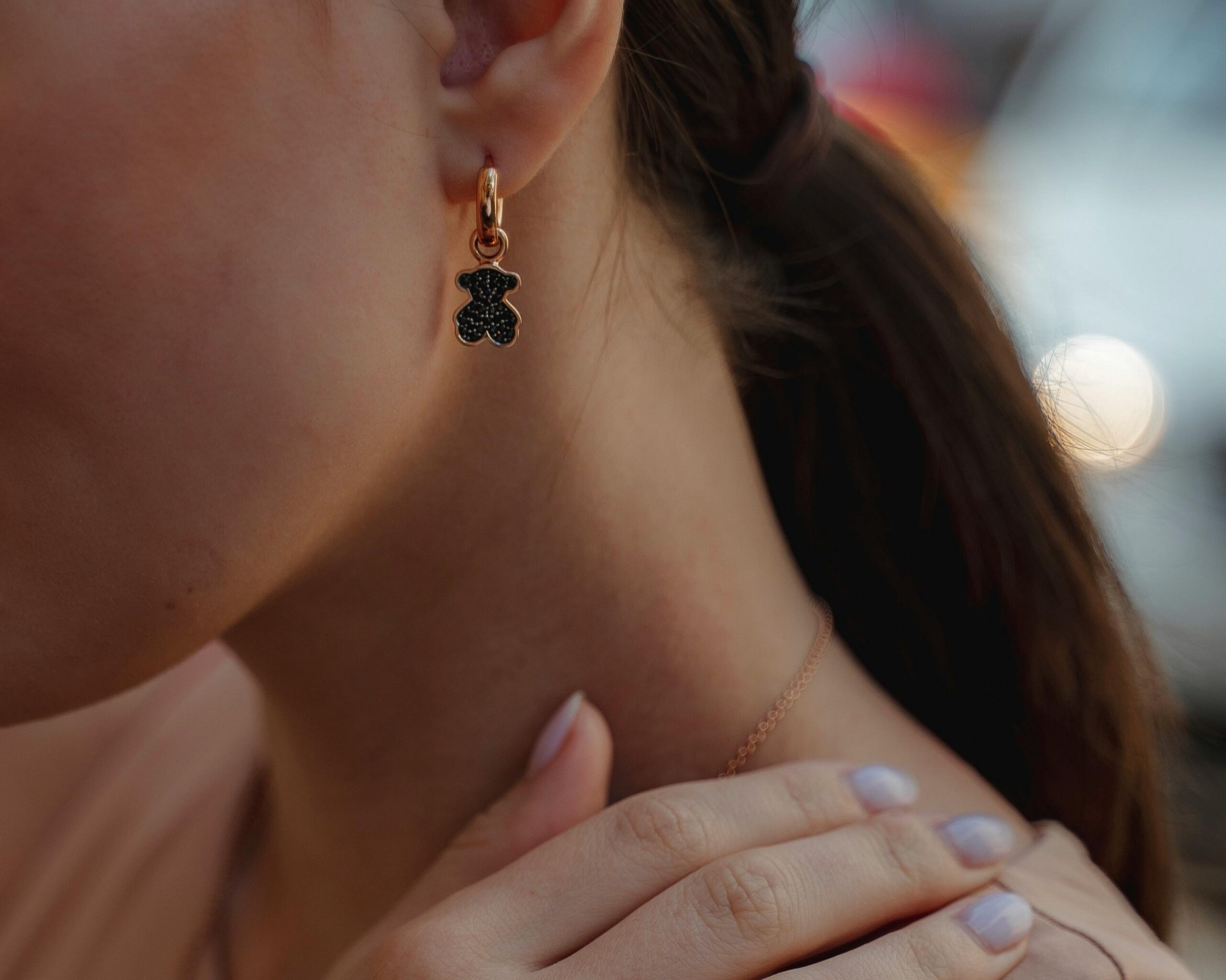 a woman pictured wearing a small gold huggie earrings whilst having lilac nails.