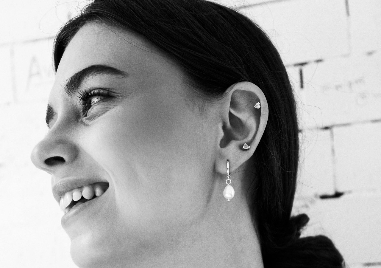 a woman wearing a huggie earring whilst smiling to the side.